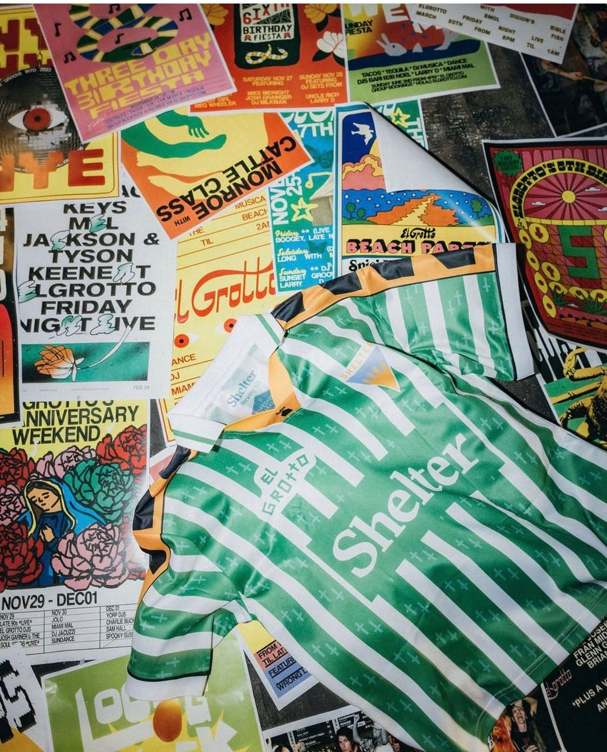 Custom El Grotto jersey flat laid over a collage of El Grotto event gig poster artwork