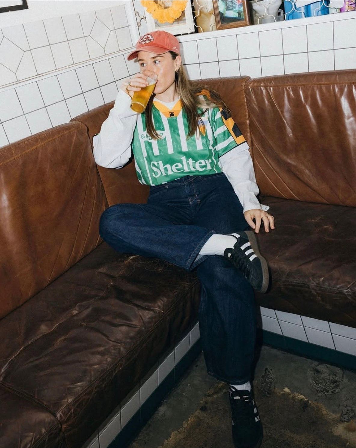 Custom El Grotto jersey for Shelter styled as streetwear, lifestyle shot on leather booth seating