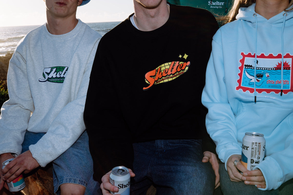 Three people wearing the Shelter range in grey, black and blue, showing printed crews and hoodies together